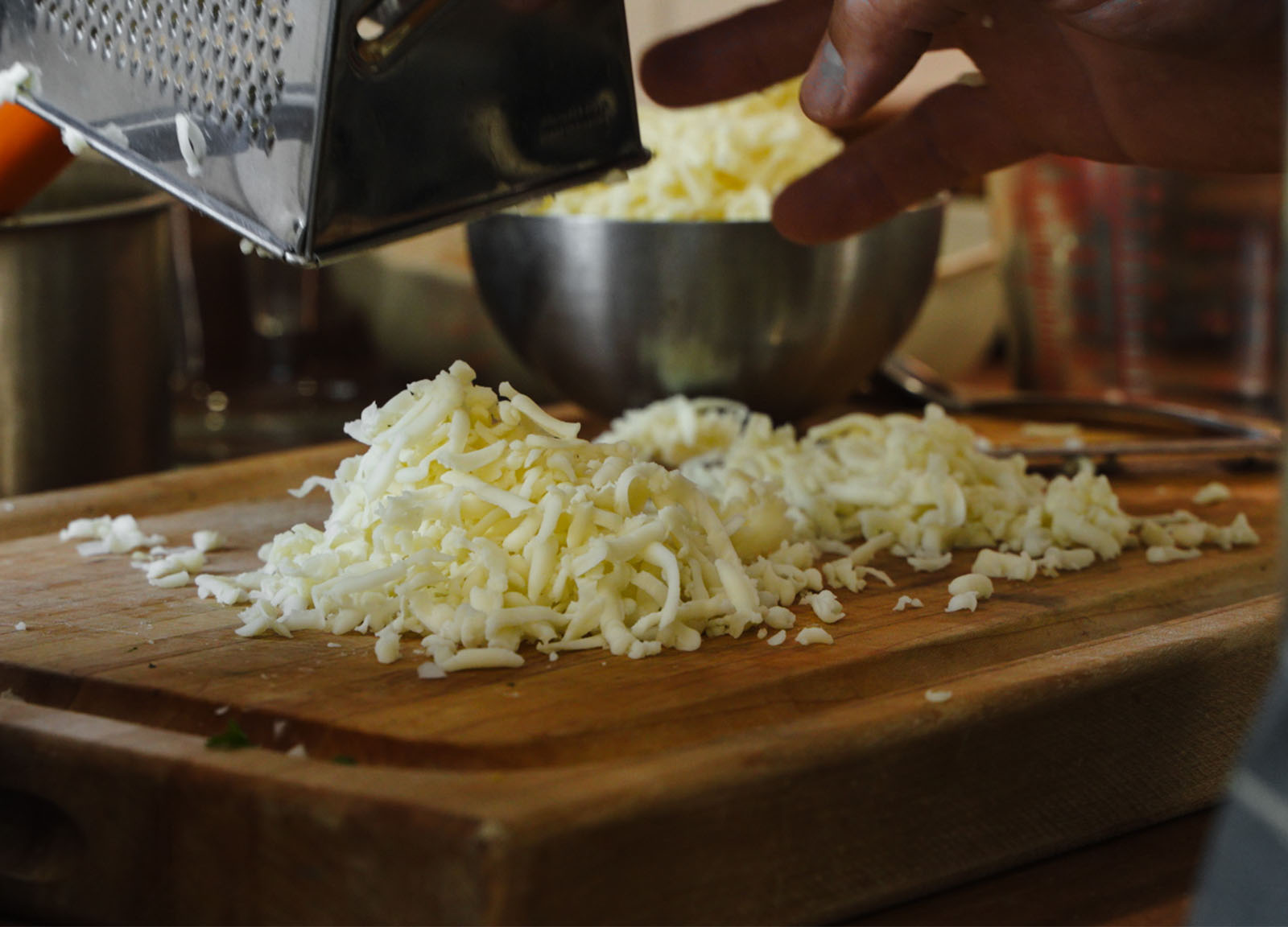 Shredded cheese on a wooden cutting board.
