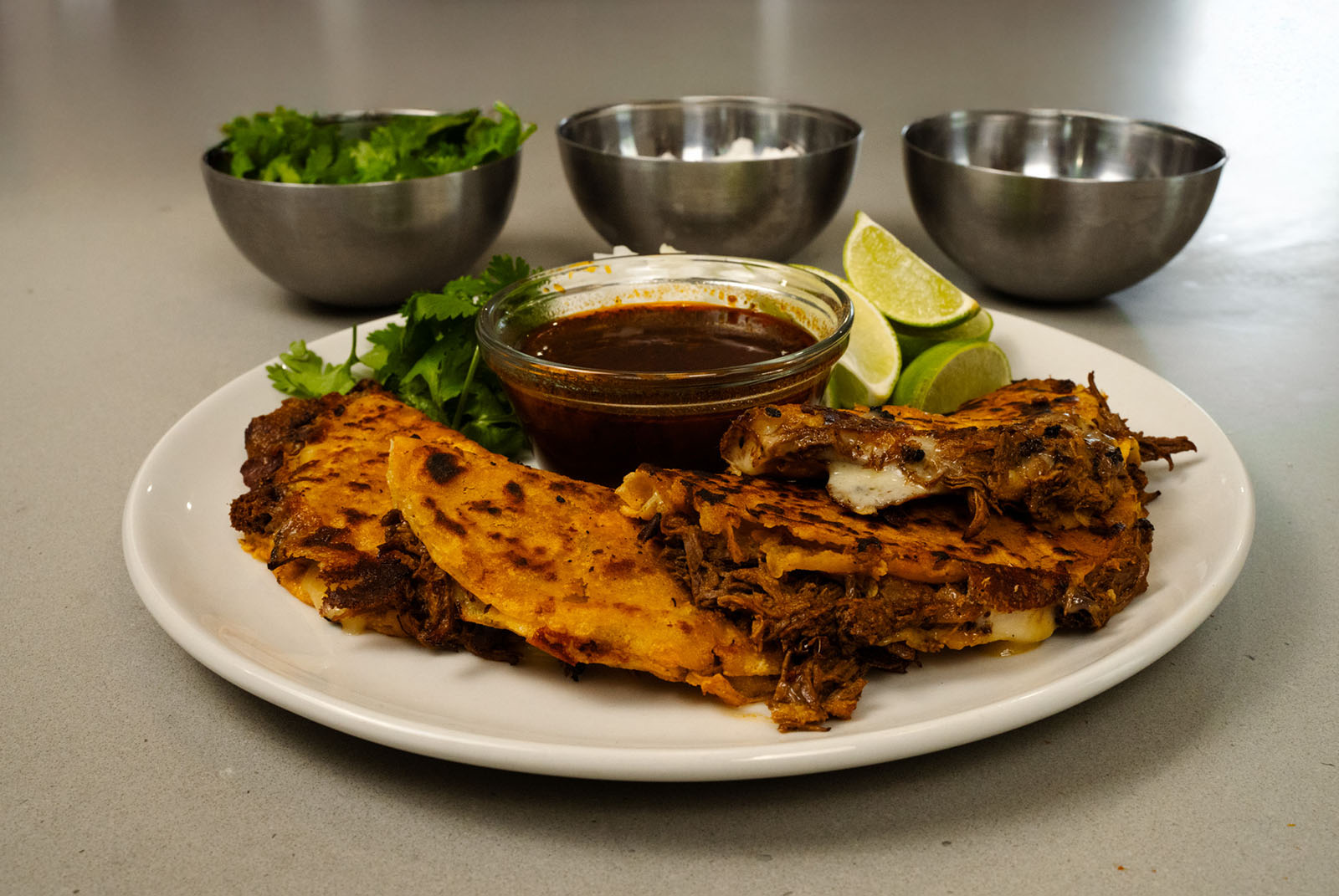 Plated duck tacos with dipping sauces.