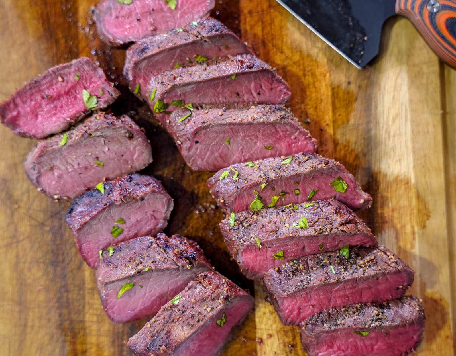 Deer backstraps cut on a wood cutting board.