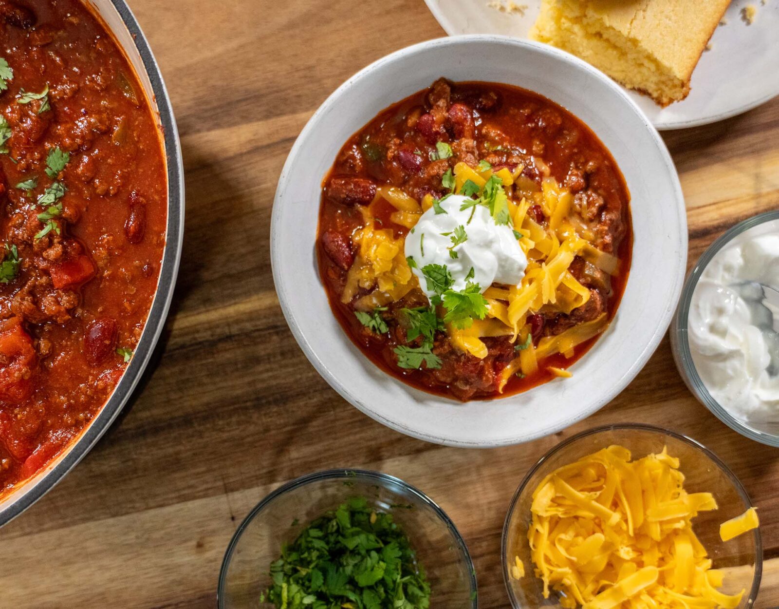 Venison chili in a bowl with a dollop of sour cream and cheese sprinkled on top.