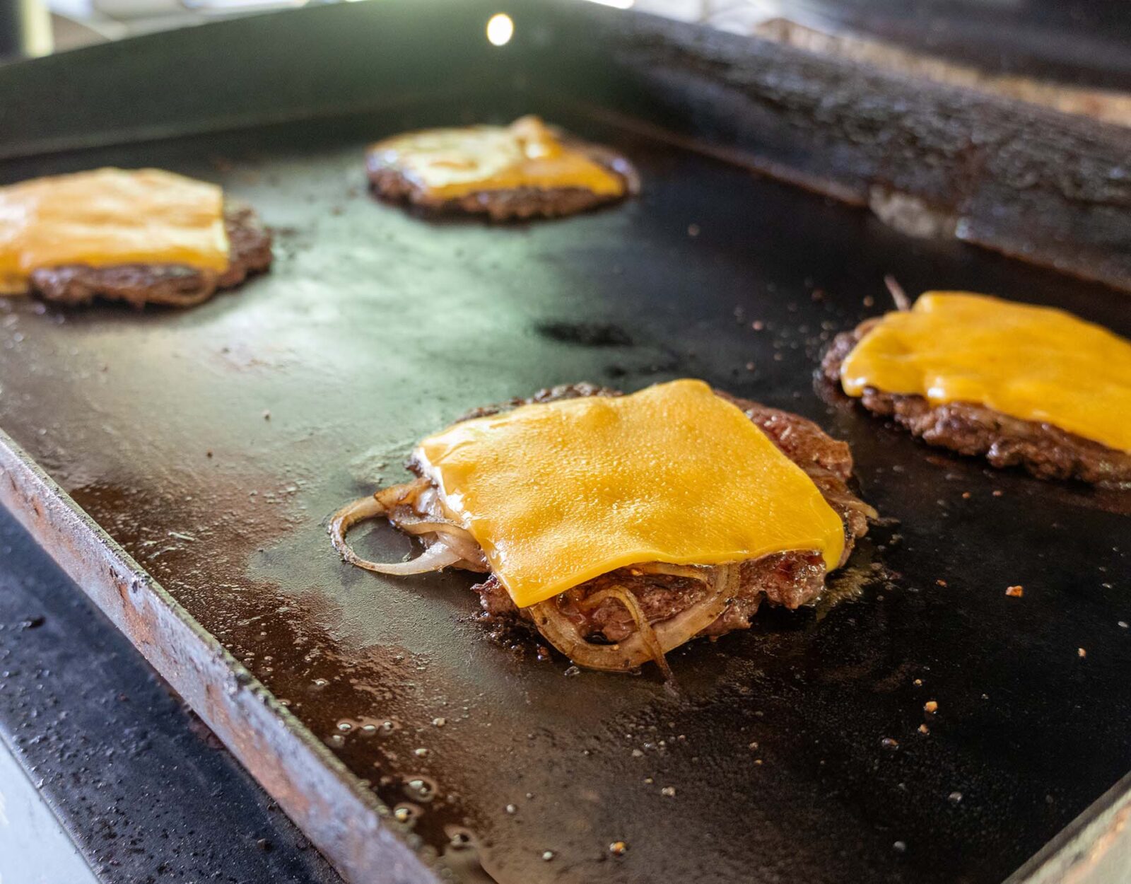 Venison burgers on a flat top grill.