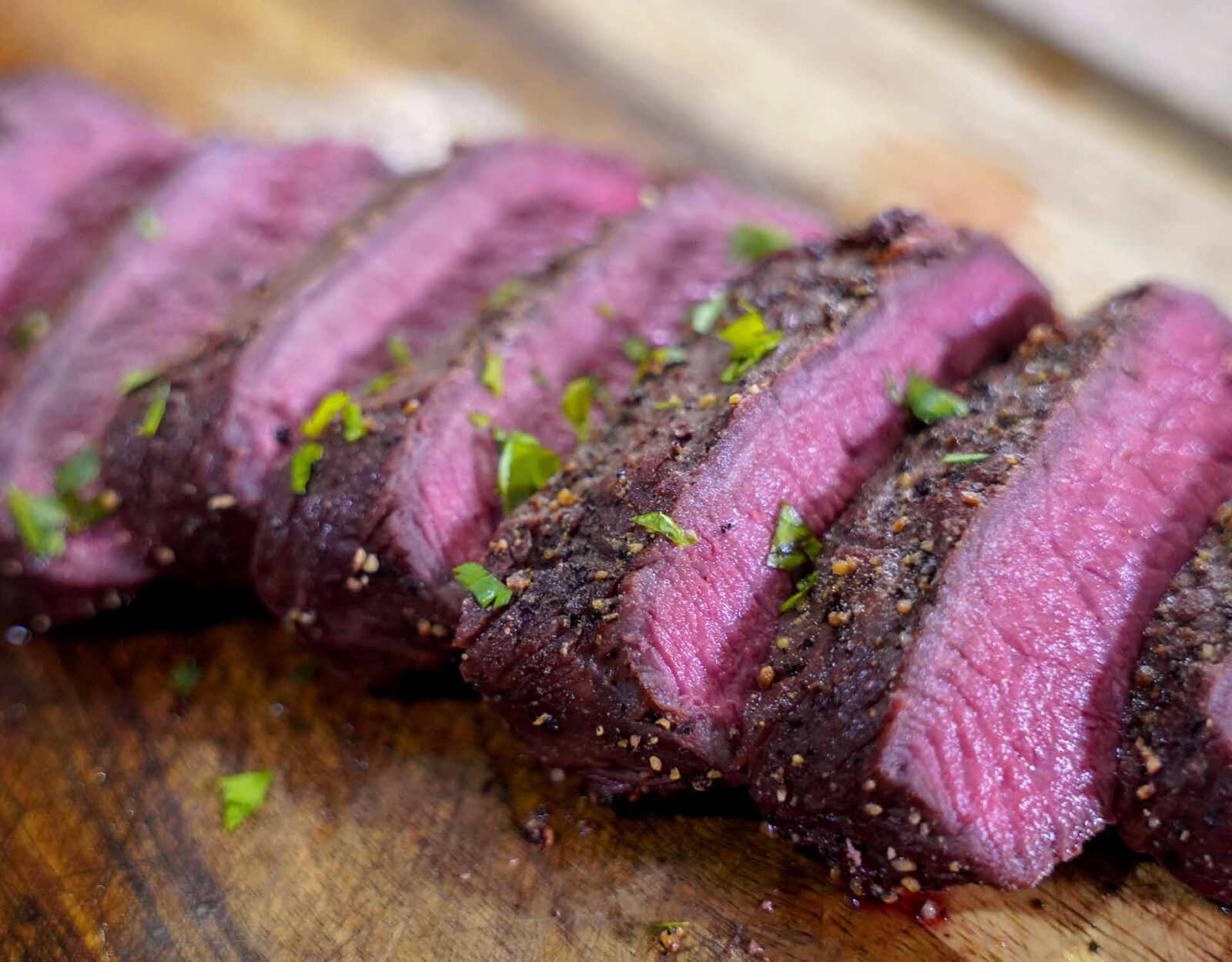 Deer backstraps cut on a wood cutting board.