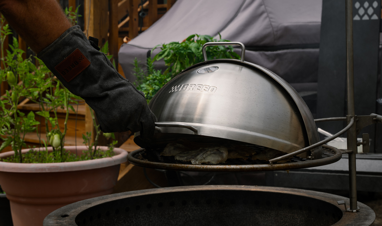 Breeo grill with a gloved hand opening the lid.