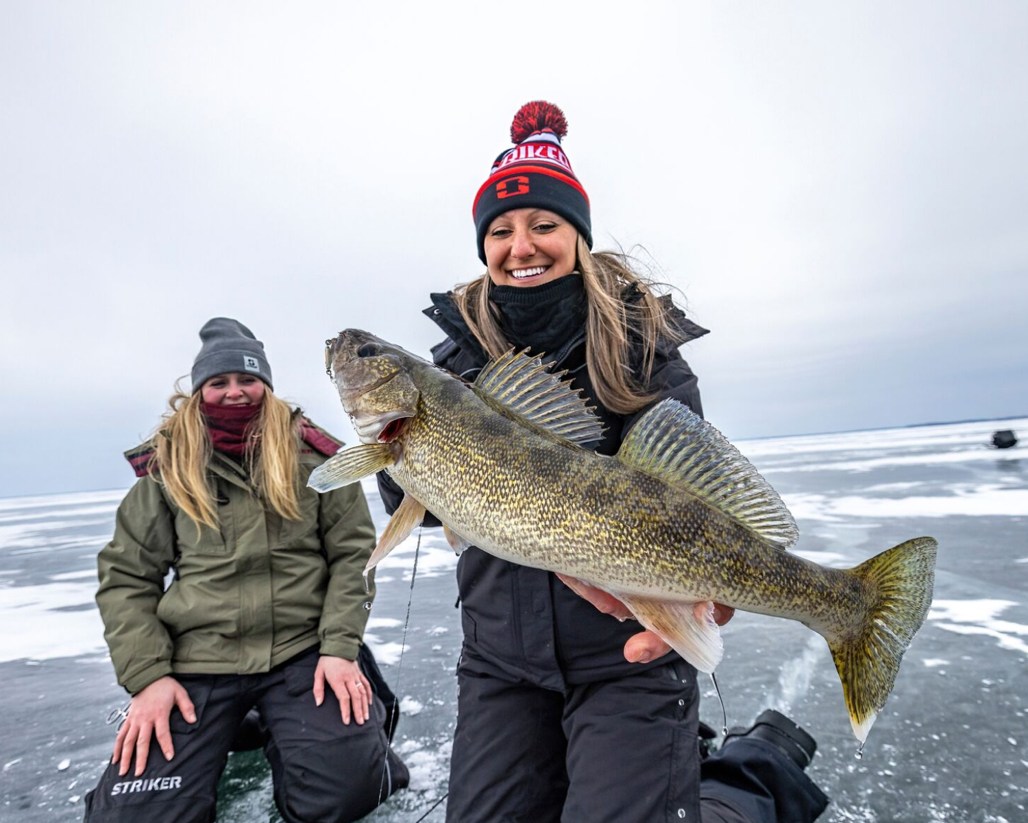 Two female anglers, with one holding a huge walleye.