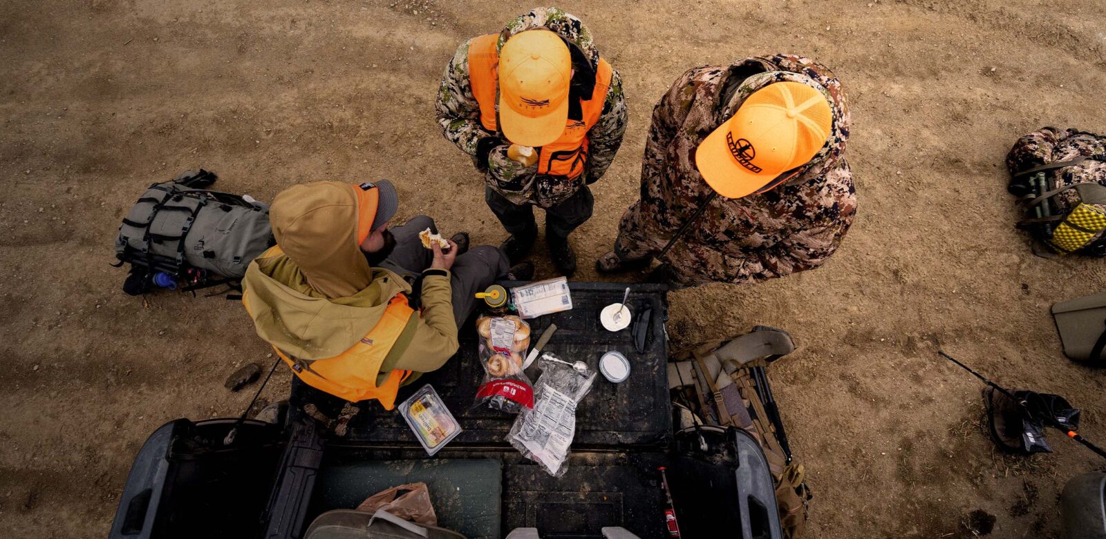 A group of hunters eats snacks at a tailgate.