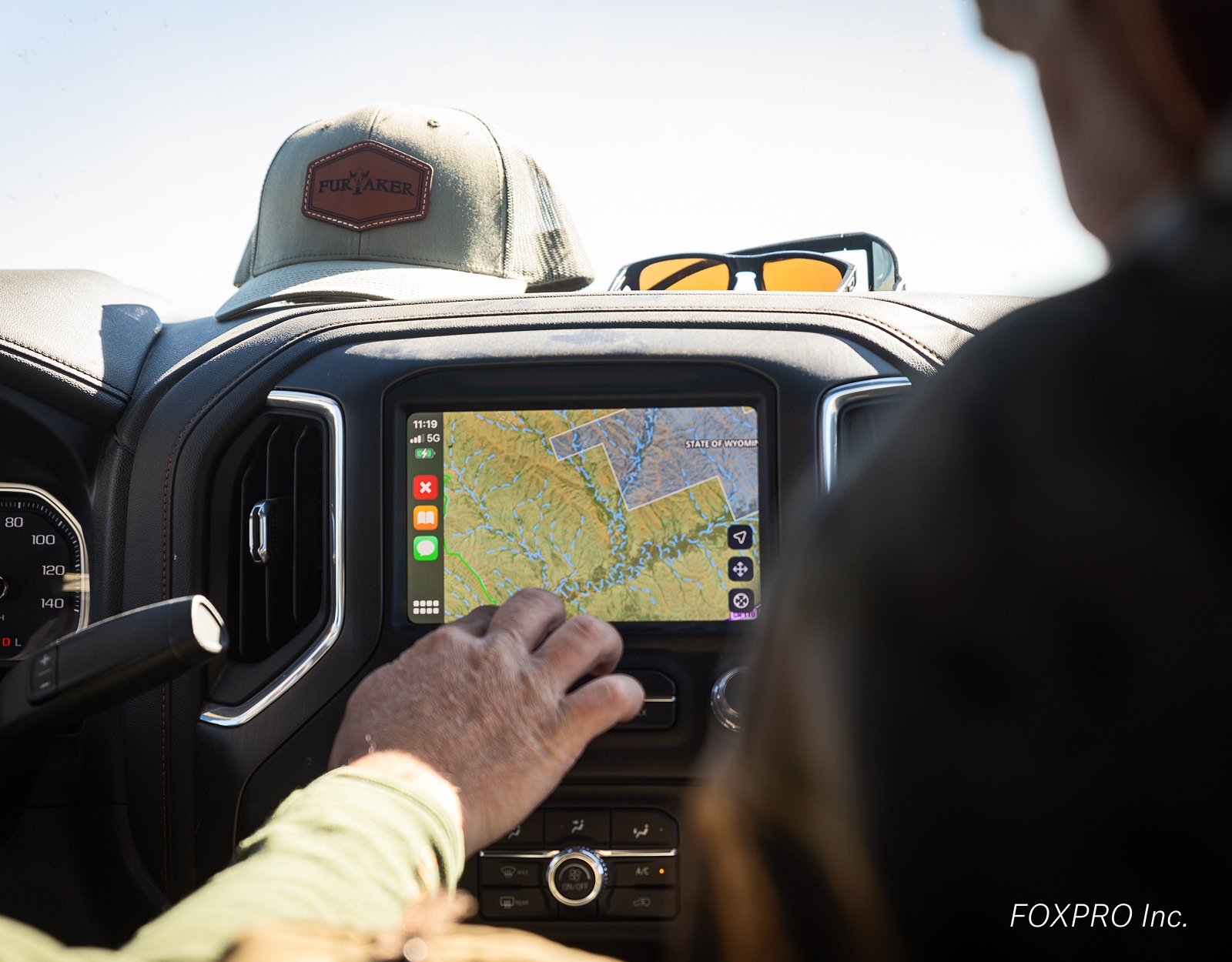 A hand navigates onX Hunt via CarPlay.