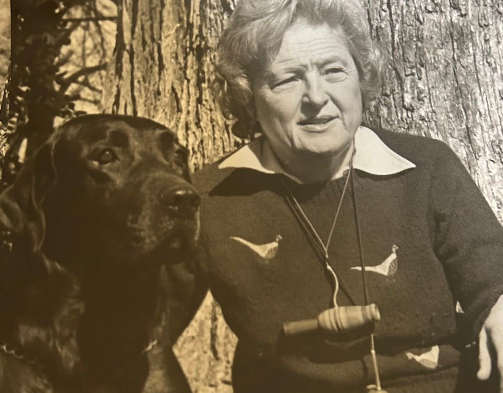 Black and white photo of a woman and a black lab.