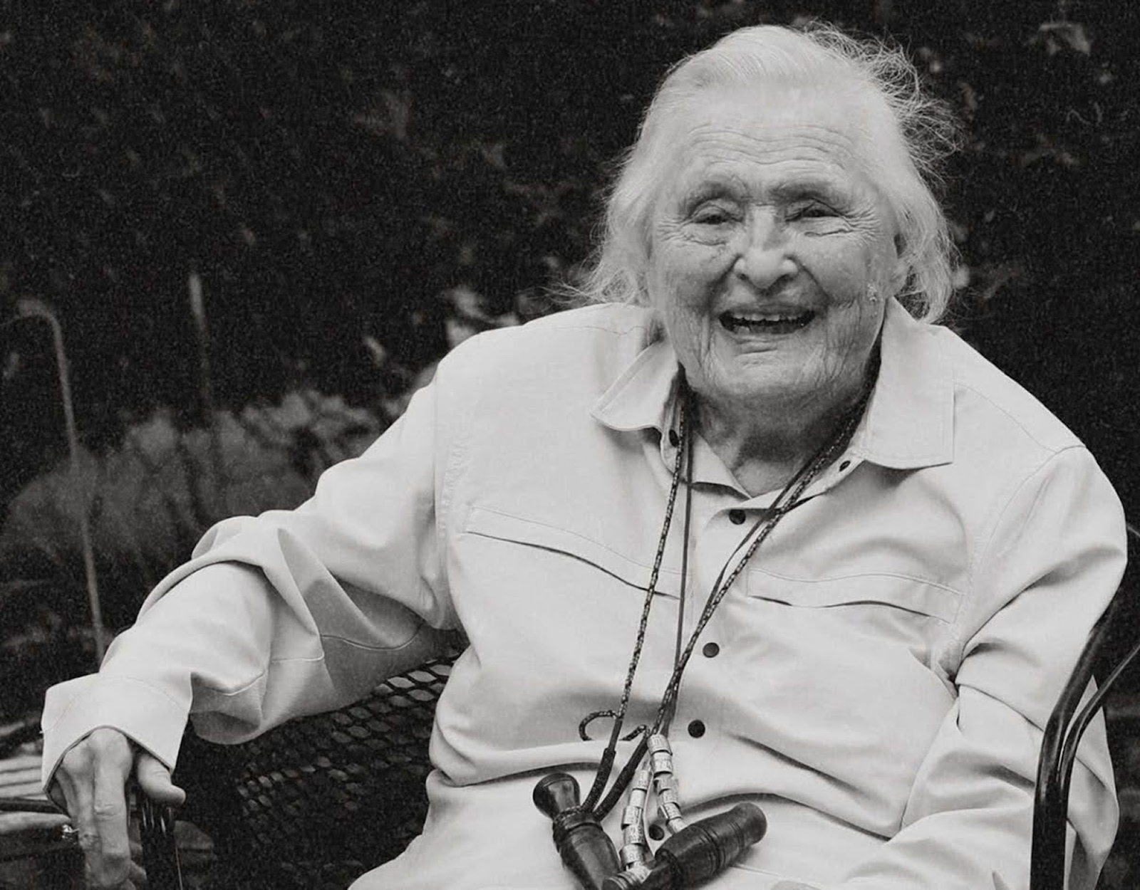 Gail Camp sits in a chair with duck calls around her neck on a lanyard.