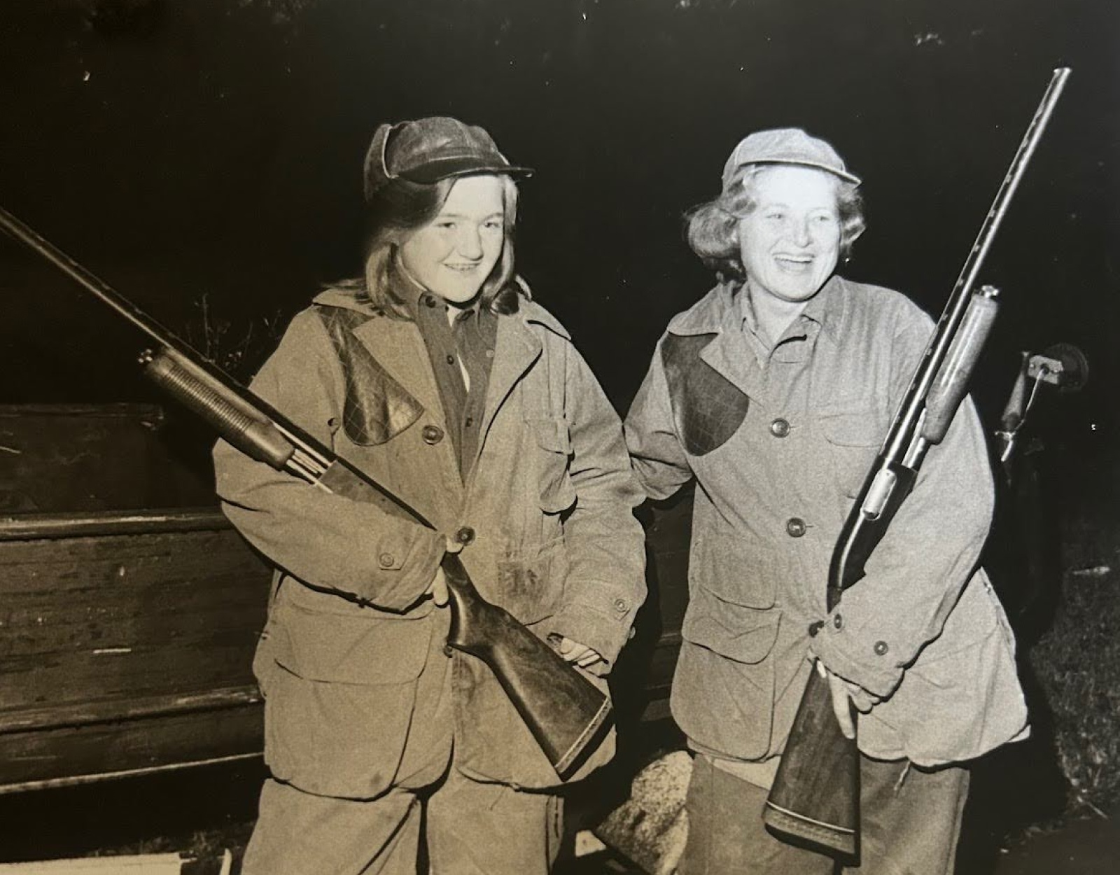 A black and white photo of two women holding shotguns.