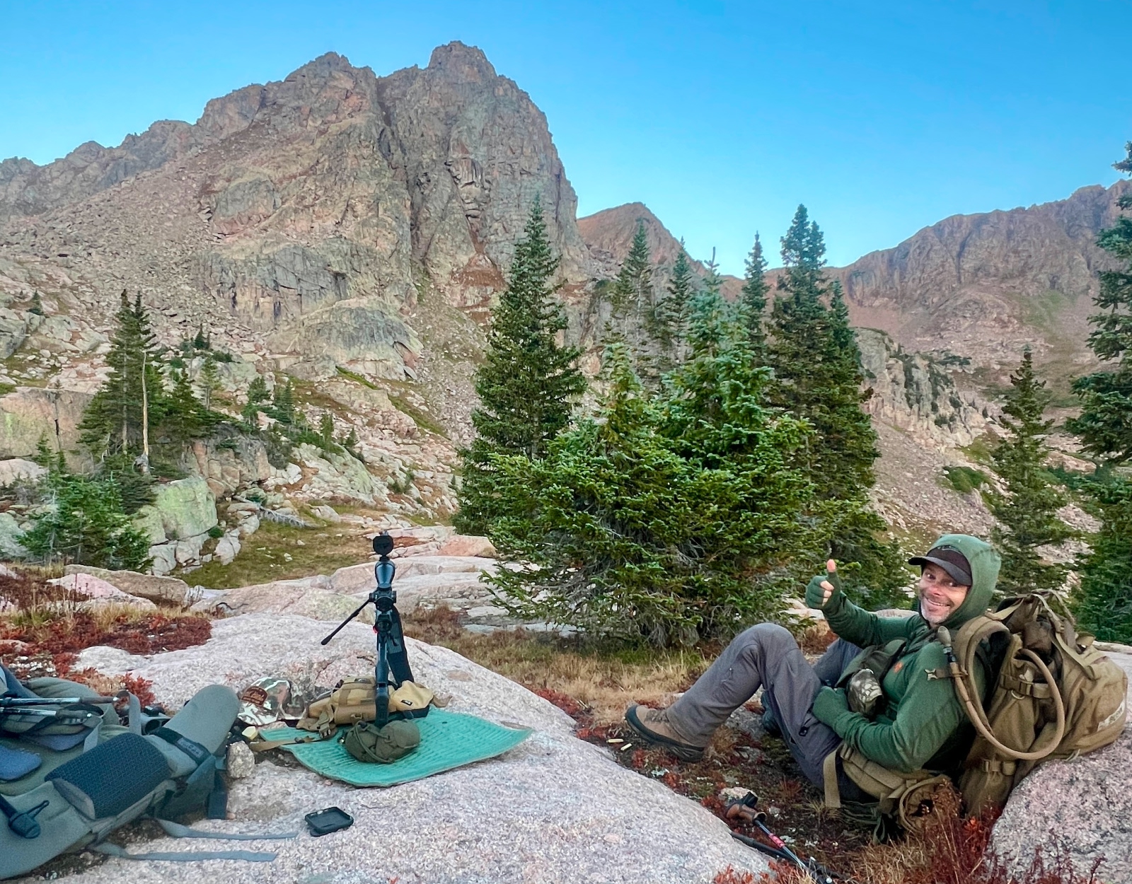 A rifle set up and a hunter giving the thumbs up.