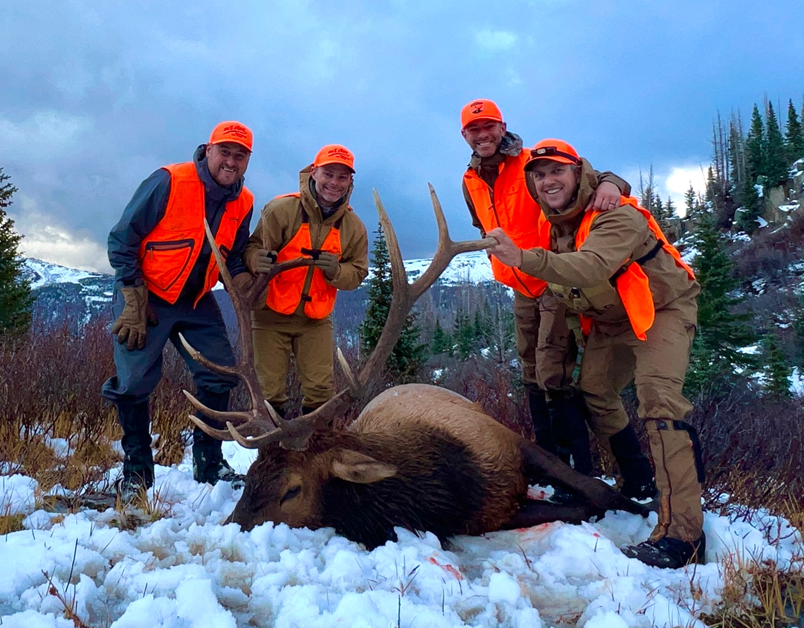 A hunter, with his hunting partners, poses with the bull elk he shot.