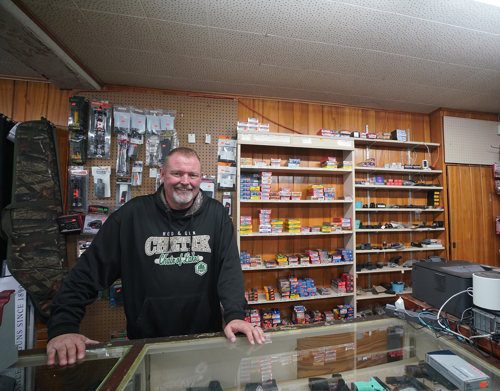 A man stands behind the counter of a hunting and fishing store.