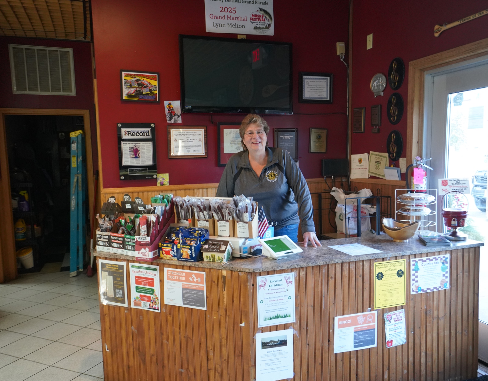 A woman stands behind the front counter of the butcher shop she owns.