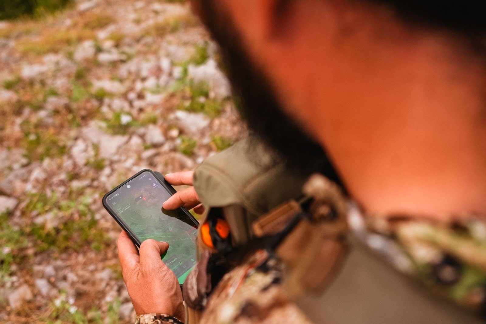 A man holds a mobile device and reviews the onX Hunt App. 