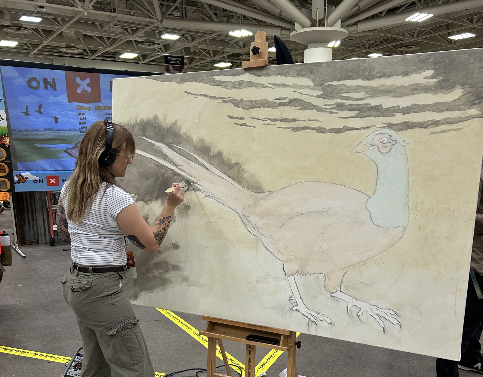 A woman creates artwork depicting a pheasant.