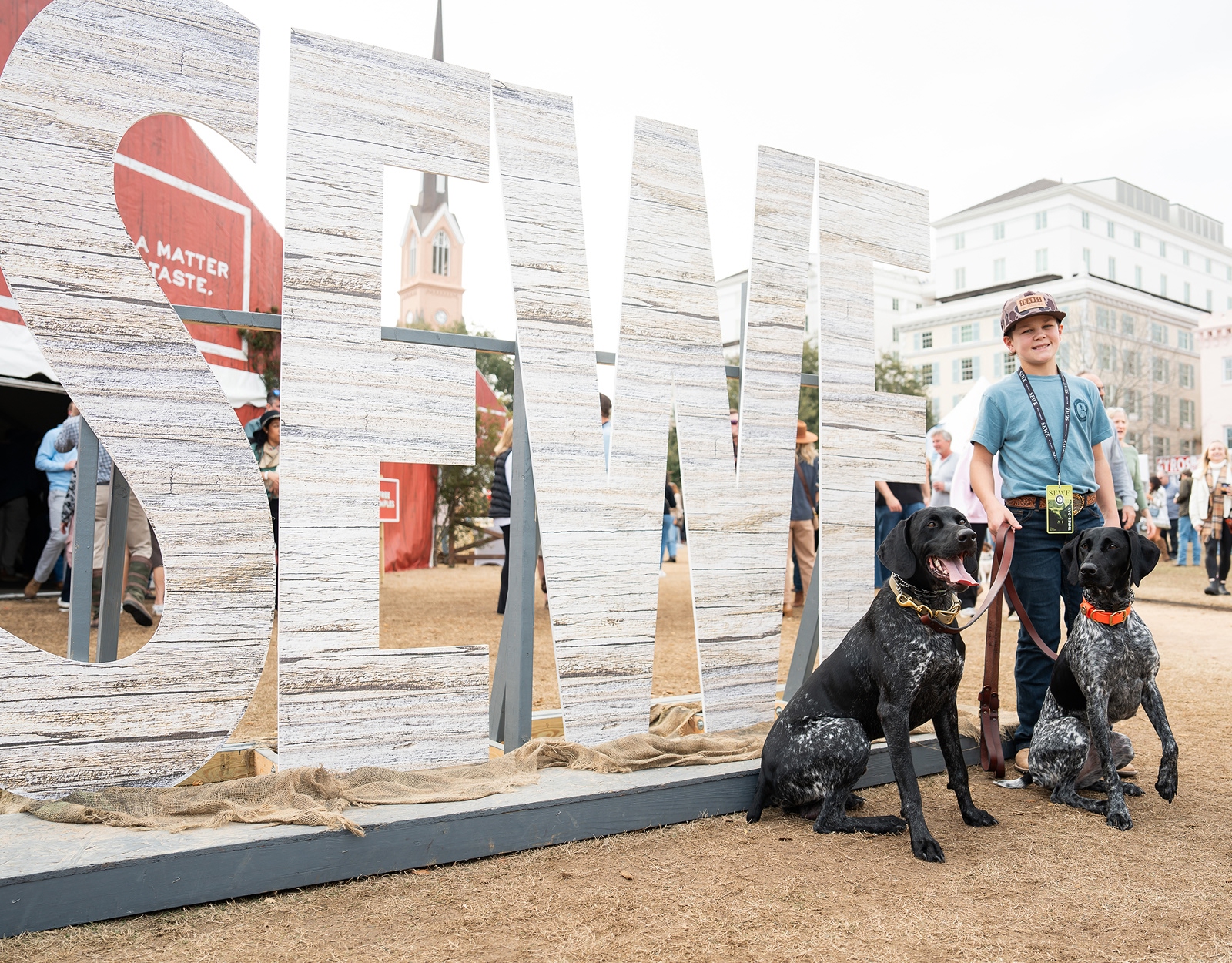 A large sign saying "SEWE" with a person posing with dogs.