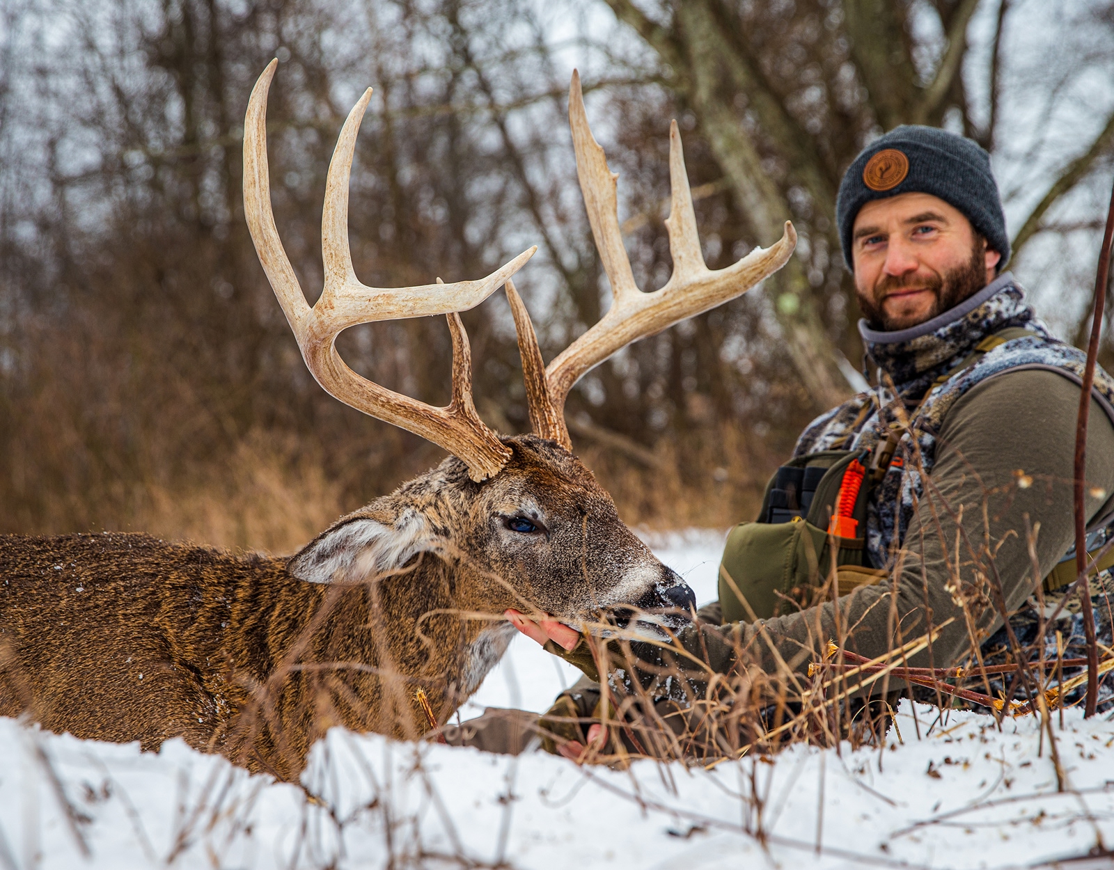 A man poses for a grip and grin with a big white tail buck. 