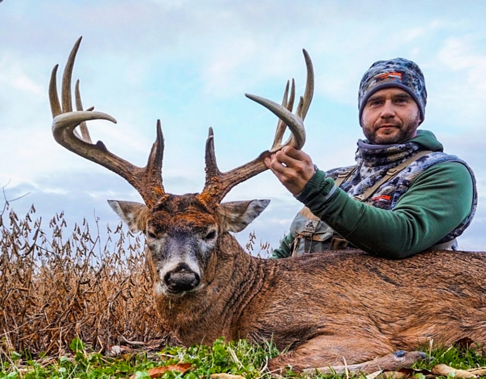 A man poses for a grip and grin with a big white tail buck.