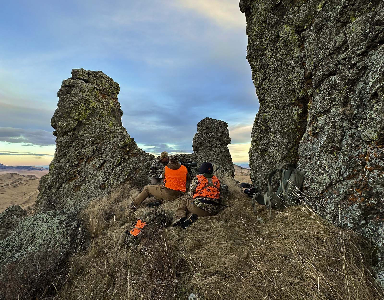 Two hunters looking over the top of a rock outcropping