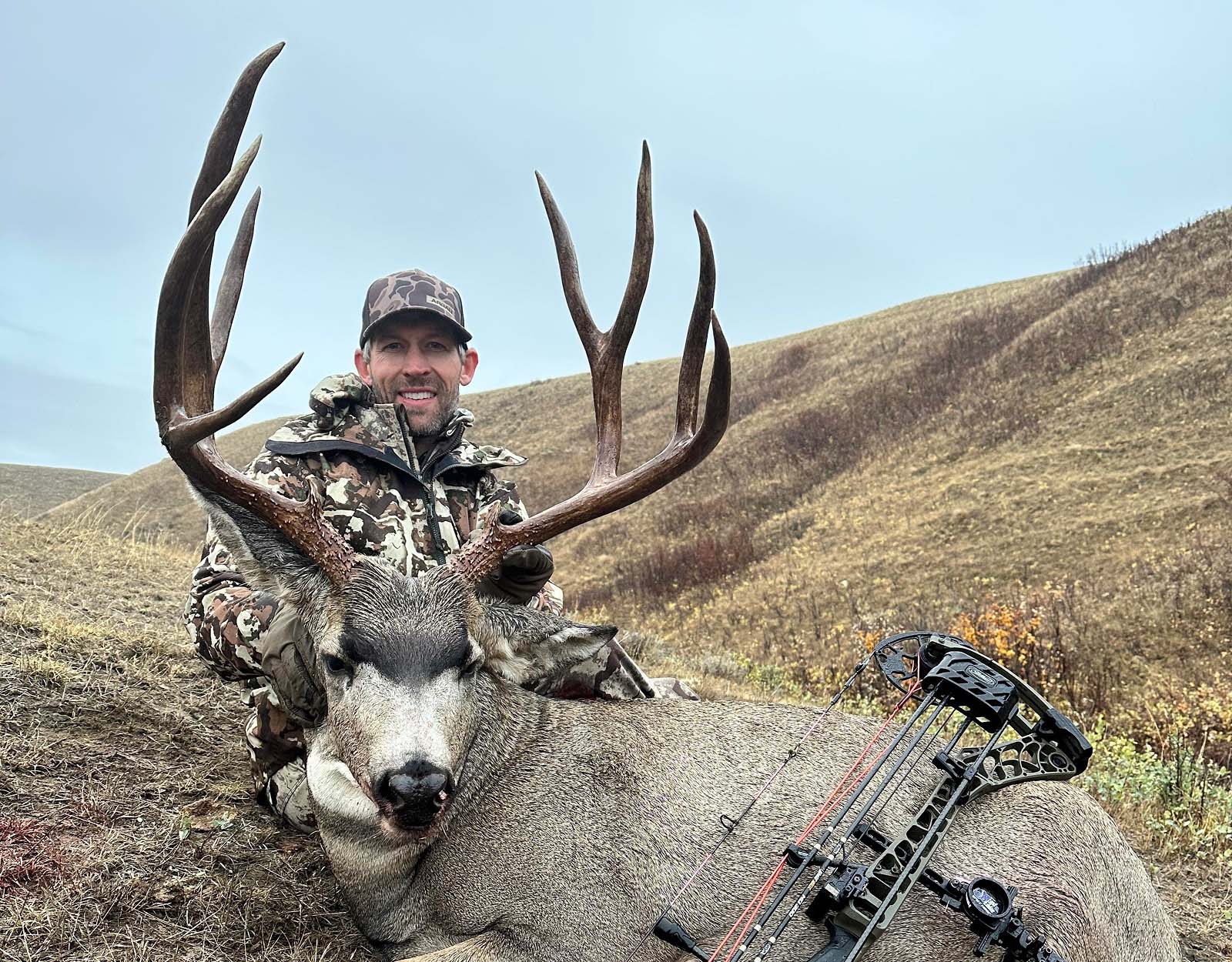 A hunter poses with the mule deer buck they harvested.