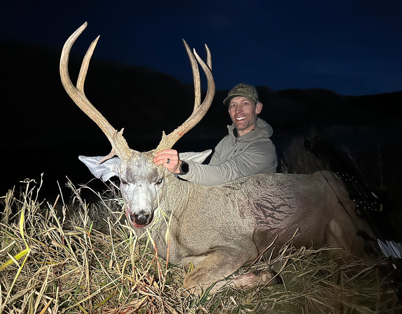 A hunter poses with the mule deer buck they harvested.