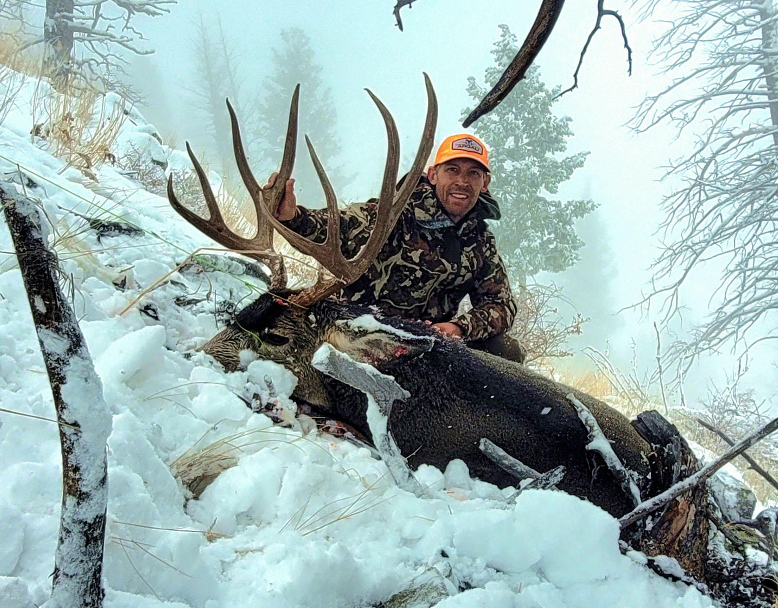 A hunter poses with the mule deer buck they harvested.