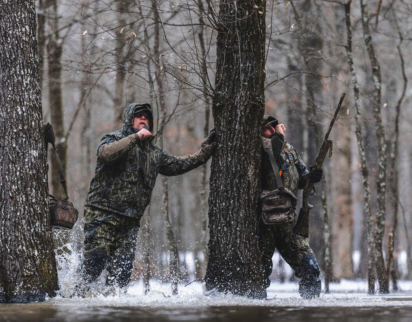 Two hunters use duck calls during a duck hunt in the rain.