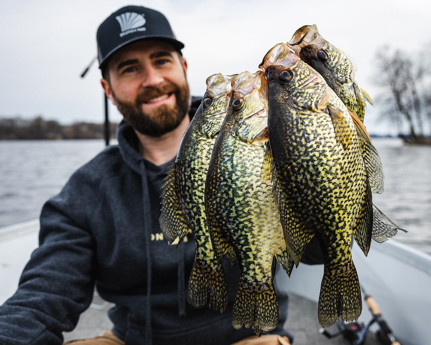 A man holds a string of crappie he caught.