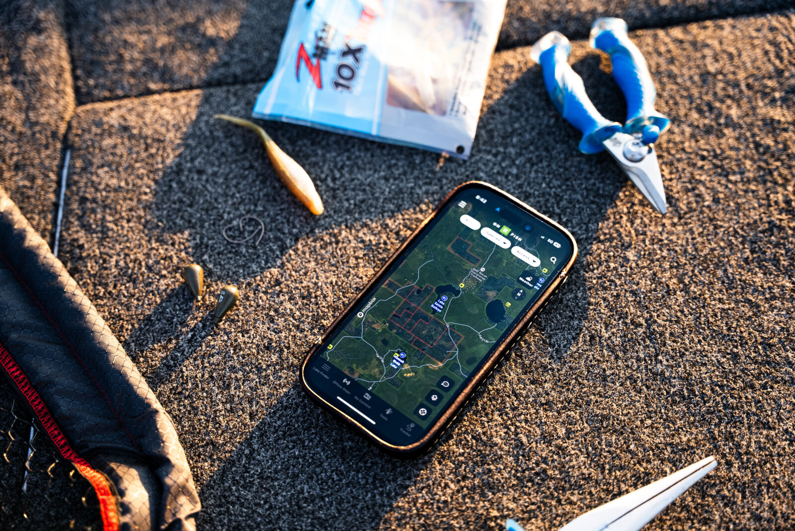 onX Fish app with a lake map shown sitting with fishing tackle