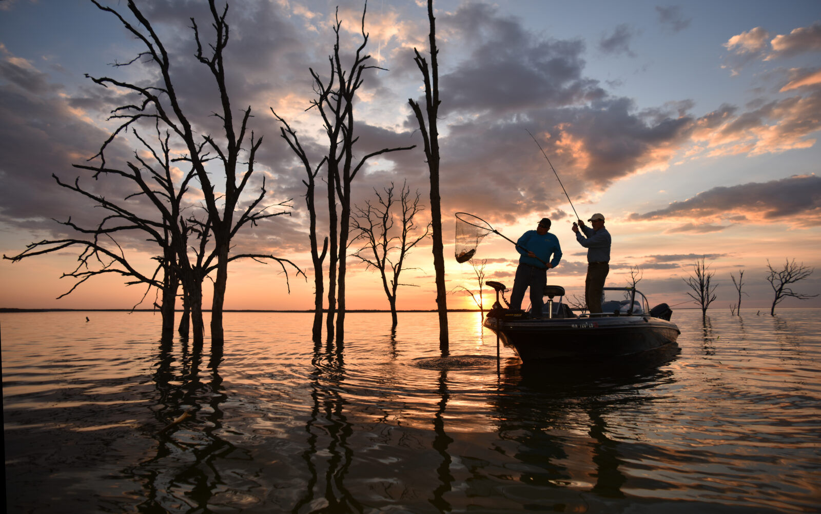 Two anglers in a boat on a North Dakota lake with a fish in their net