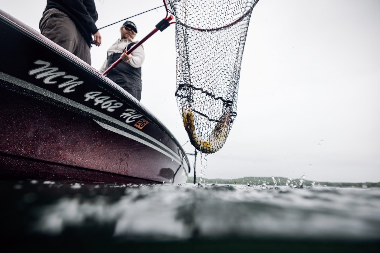 two anglers on a boat with a fish in a net