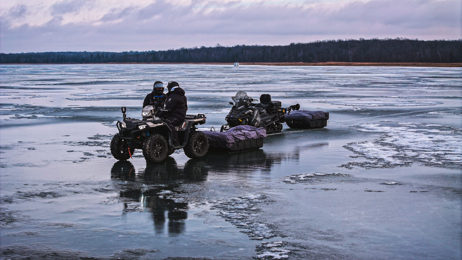 ice fisherman snowmobiling on a frozen lake