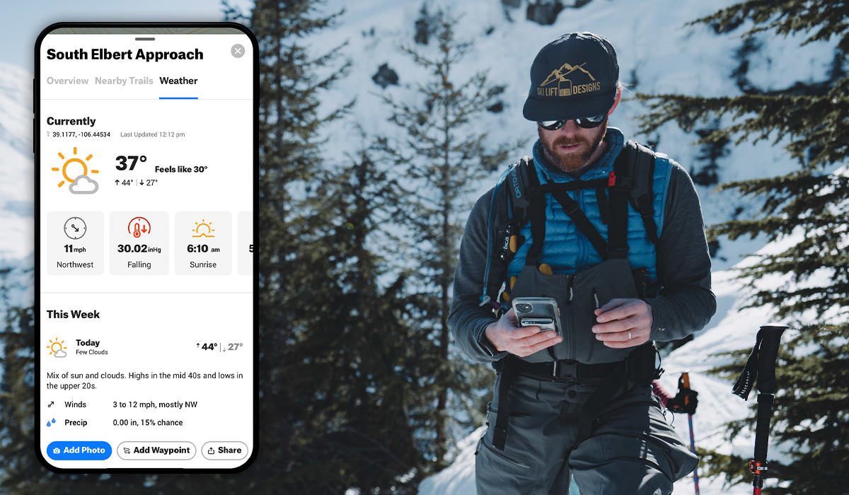 A backcountry skier looking at the onX Backcountry app on their phone with the current and forecasted weather. 