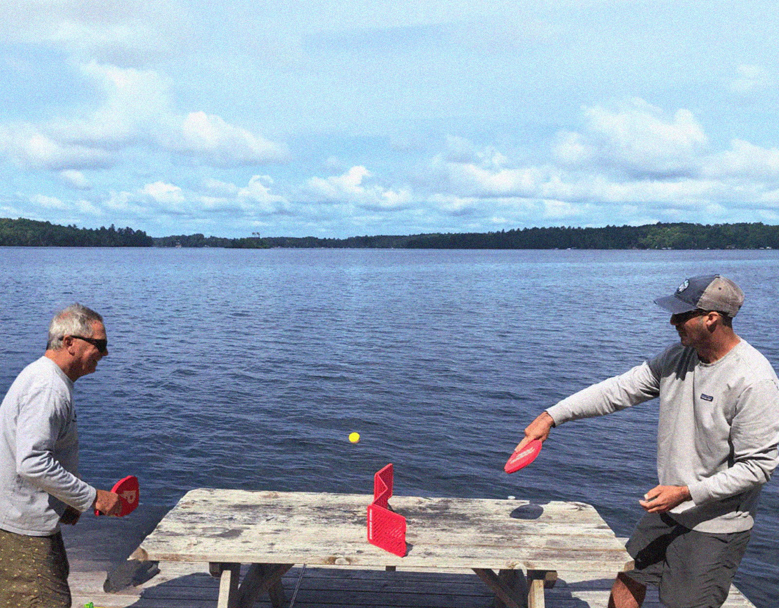 2 men playing pepper pong by a lake 